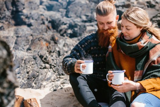 Couple with mugs of hot chocolate on Rock beach