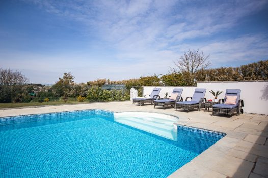 Four recliners alongside the pool at Gwel Mor