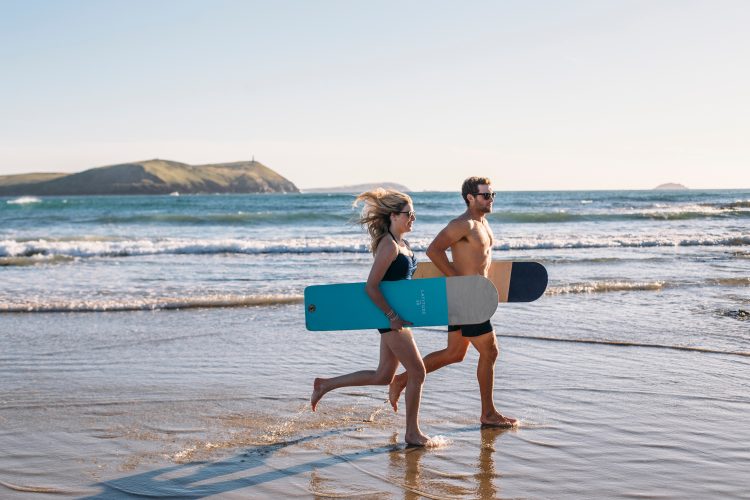 Couple bellyboarding on Polzeath Beach